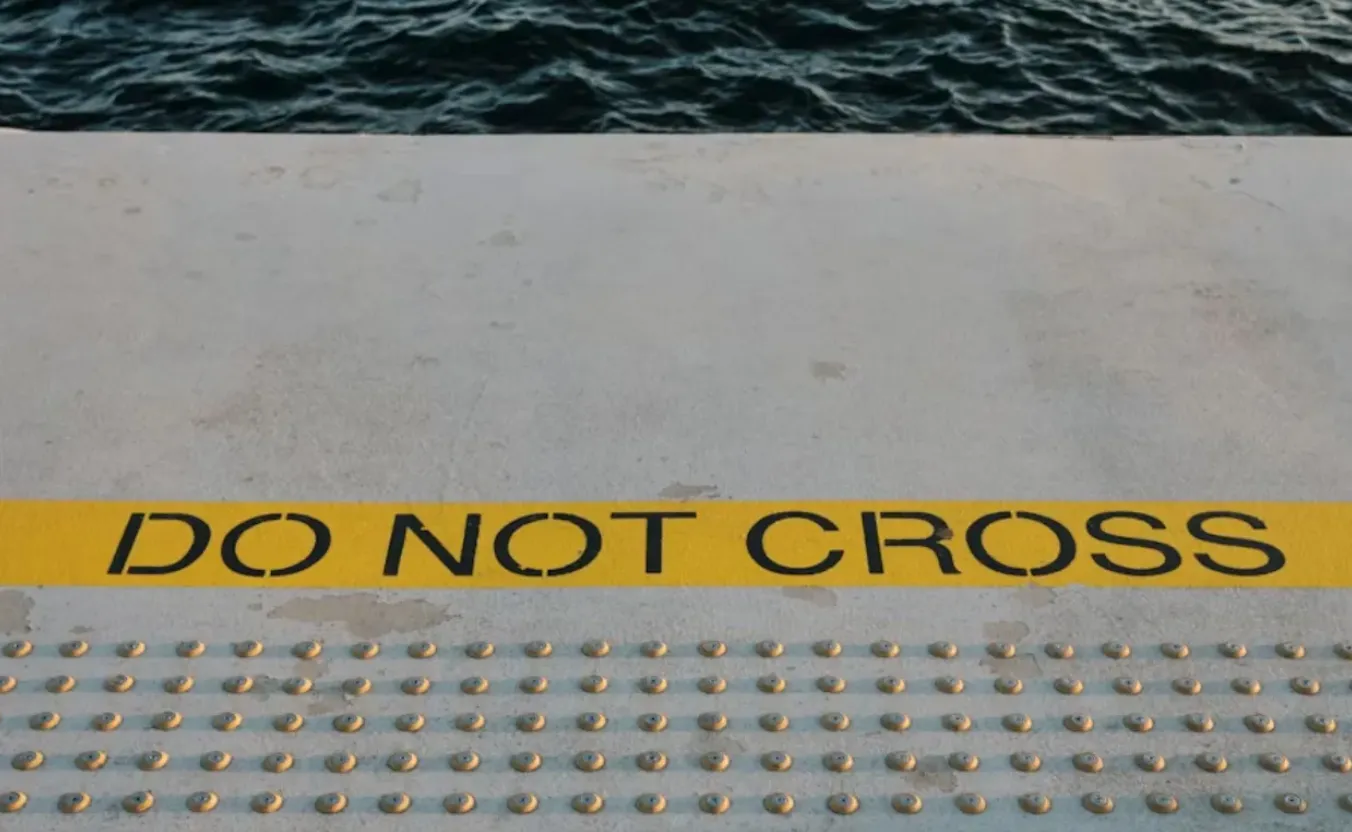 Orange construction caution tape reading "DO NOT CROSS" stretched across a boundary.